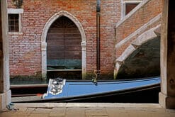 A photo of a gondola passing by the Libreria Acqua Alta in Venice, Italy by Photographer Scott Allen Wilson