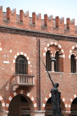 Photo of a statue of a woman holding a sword in front of the walls of Palazzo della Ragione in Verona, Italy captured by Photographer Scott Allen Wilson