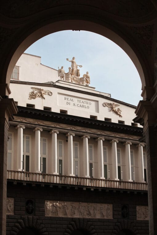 Artistic photograph of the Real Teatro di San Carlo located in Naples, Italy peaking out behind an arch wall taken by Photographer Scott Allen Wilson