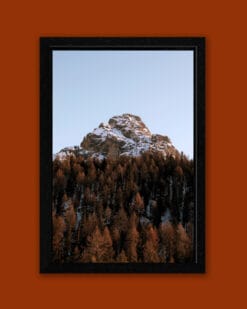 Beautiful autumnal framed photo of a snow-capped mountain of the Dolomites, Italy surrounded by reddish trees taken by Photographer Scott Allen Wilson.