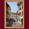 Colorful framed print of a man riding a bike in a street of Lazise, Italy taken by Photographer Scott Allen Wilson.