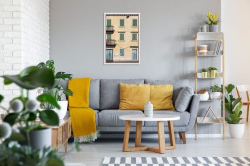 Gray living room decoration with yellow details and a framed print of a yellow building with symmetric green and blue window frames taken in Peschiera del Garda, Italy by Photographer Scott Allen Wilson.