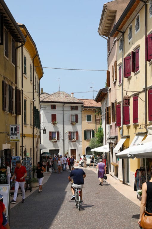 Colorful photo of a man riding a bike in a street of Lazise, Italy taken by Photographer Scott Allen Wilson.