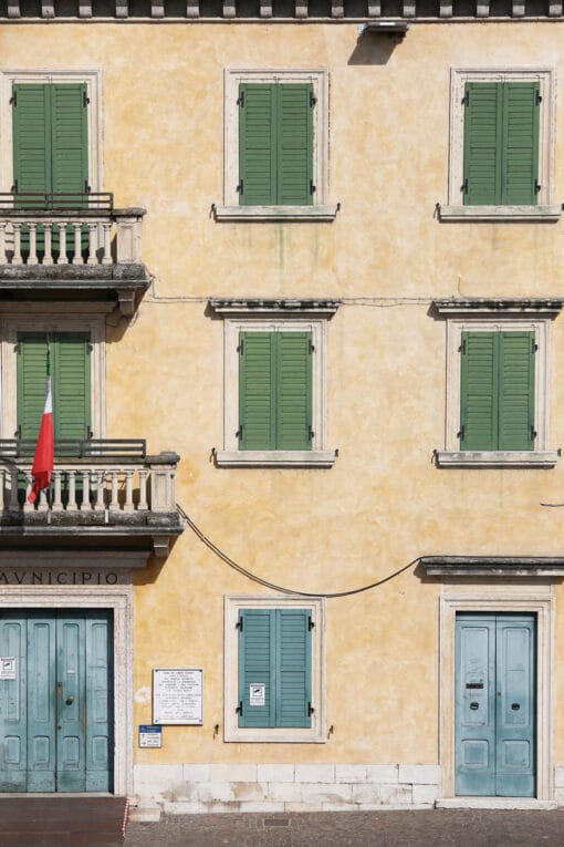 Yellow building with symmetric green and blue window frames taken in Peschiera del Garda, Italy by Photographer Scott Allen Wilson.