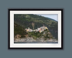 Black framed artistic print of the town of Corniglia in Cinque Terre, Italy, on a green hill. By Photographer Scott Allen Wilson.