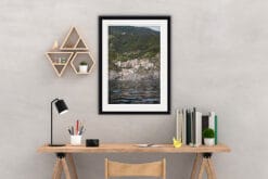 The print of Manarola in Cinque Terre, Italy, hangs in an office with wooden furniture. By Photographer Scott Allen Wilson.