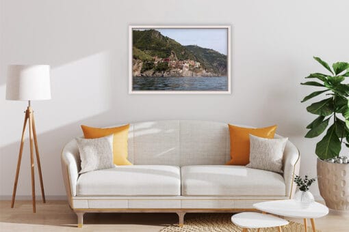 A white and wooden decored living room is completed by a view of Manarola in Cinque Terre, Italy.