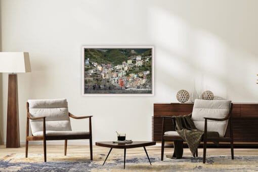 The print of Rio Maggiore, Italy, by Photographer Scott Allen Wilson, adds a pop of color to a minimal room with wooden decor.