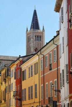 A print of colorful buildings and a clock tower in the background contrasting with the blue sky in Parma. By Photographer Scott Allen Wilson