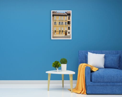 A print of a bright yellow house in Parma hung in a blue room with minimal decor. By Photographer Scott Allen Wilson.