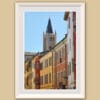 A white framed print of colorful buildings and a clock tower in the background contrasting with the blue sky in Parma. By Photographer Scott Allen Wilson