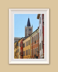 A white framed print of colorful buildings and a clock tower in the background contrasting with the blue sky in Parma. By Photographer Scott Allen Wilson