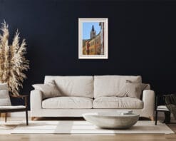 A print of a clock tower in Parma hung in a dark room with wooden decor and a light colored sofa. By Photographer Scott Allen Wilson.