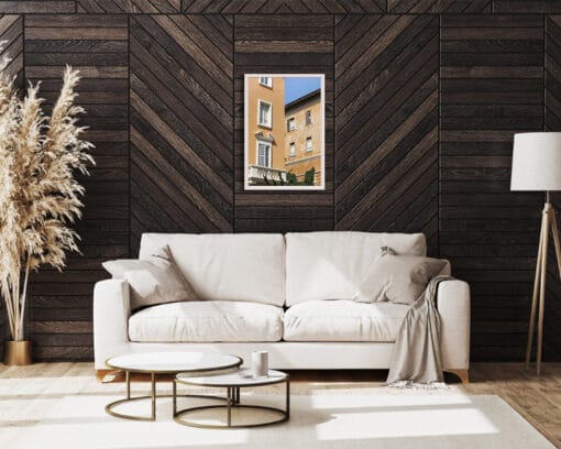 A white framed print of butter-colored buildings in Pescara, Italy, hanging in a living room with wooden walls and white decor. By Photographer Scott Allen Wilson.