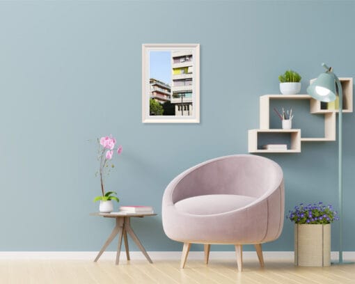 A white framed print of colorful buildings in Pescara, Italy, standing out behind modern buildings hanging in a modern living room with neutral color decor. By Photographer Scott Allen Wilson.