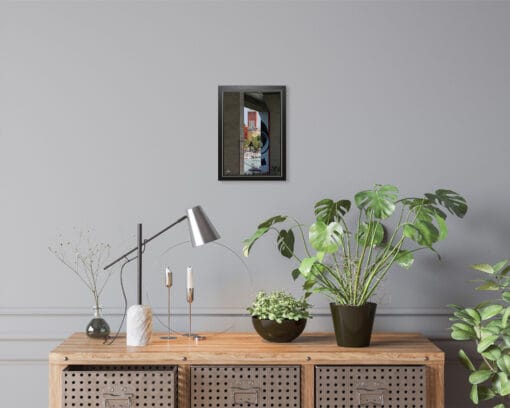 A black framed print of a square with a clock tower in Pescara, Italy, hanging in a room with wooden decor. By Photographer Scott Allen Wilson.