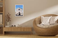 A white framed print of the façade of San Francesco Church in Lucca, Italy, hanging in a living room with wooden decor. By Photographer Scott Allen Wilson.