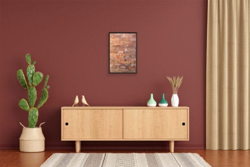 A dark brown framed print of a red brick wall in Lucca, Italy, hanging in a room with minimal wooden decor. By Photographer Scott Allen Wilson.