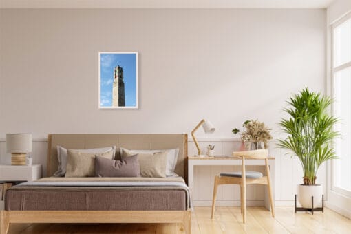 A white framed print of a monument in Lucca, Italy, hanging in a minimal living room with wooden decor. By Photographer Scott Allen Wilson.