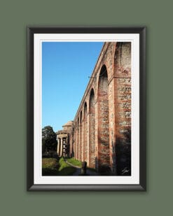 A black framed print of the red brick columns and archs leading to a church in the city of Lucca, Italy. By Photographer Scott Allen Wilson.