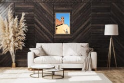 A wooden framed print of a red brick tower in Lucca, Italy, hanging in a modern living room with white sofa and black wallpaper. By Photographer Scott Allen Wilson.