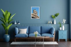 A white framed print of the Church of San Michele in Foro in Lucca, Italy, hanging in a modern living room with blue decor. By Photographer Scott Allen Wilson.