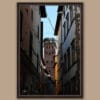 A dark brown framed print of Torre Guinigi in the city of Lucca, Italy, with some bell towers visible. By Photographer Scott Allen Wilson.