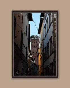 A dark brown framed print of Torre Guinigi in the city of Lucca, Italy, with some bell towers visible. By Photographer Scott Allen Wilson.