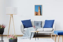 A wooden framed print of San Francesco Church in Lucca, Italy, hanging in a minimal living room with wooden furniture and white and blue decor. By Photographer Scott Allen Wilson.