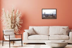 A dark brown framed print of Lucca, Italy, hanging in a pink living room with modern furniture. By Photographer Scott Allen Wilson.