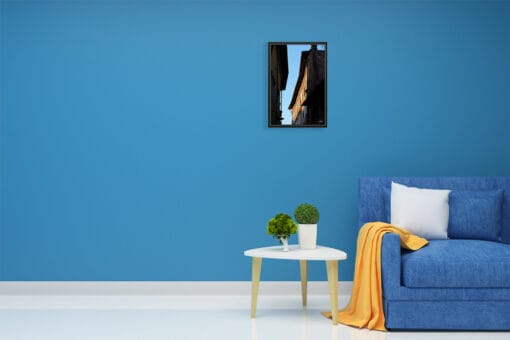 A black framed print of buildings in Lucca, Italy, hanging in a blue room. By Photographer Scott Allen Wilson.