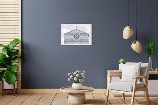 A white framed print of the façade of San Francesco Church in Lucca, Italy, hanging in a modern living room with wooden furniture. By Photographer Scott Allen Wilson.