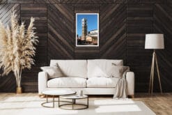 A white framed print of the San Martino Cathedral tower in the city of Lucca, Italy, hanging in a minimal living room. By Photographer Scott Allen Wilson.