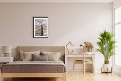 A black framed print of a view of the city of Lucca, Italy, hanging in a minimal living room with wooden decor. By Photographer Scott Allen Wilson.