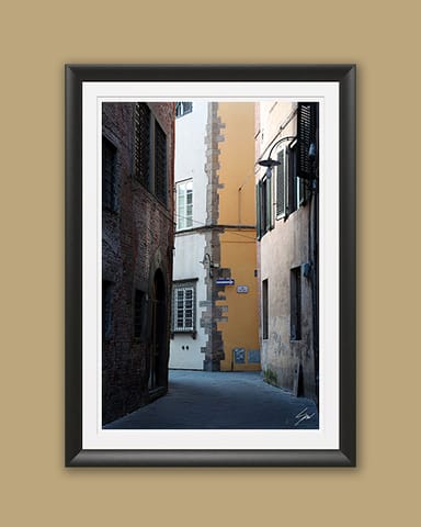 A black framed print of a view of Via Del Toro in the city of Lucca, Italy. By Photographer Scott Allen Wilson.