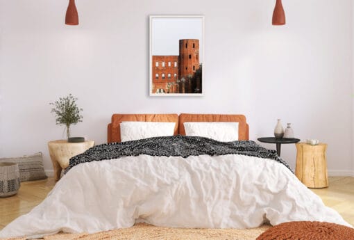 A white framed print of Porta Palatina in Torino, Italy, hanging in a modern bedroom. By Photographer Scott Allen Wilson.