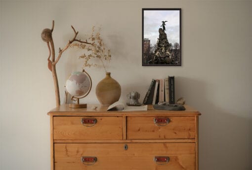 An ebony framed print of the sculpture of Piazza Statuto in Torino, Italy, hanging in a minimal room with wooden decor. By Photographer Scott Allen Wilson.