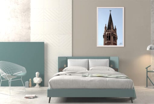 A white framed print of a pointy tower in Torino, Italy, hanging in a minimal bedroom. By Photographer Scott Allen Wilson.