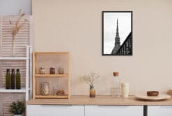 A b&w framed print of the dome of the Mole Antonelliana in Torino, Italy, hanging in a minimal room with wooden furniture. By Photographer Scott Allen Wilson.