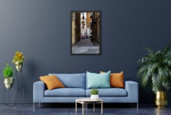 A black framed print of a cobblestone street in Torino, Italy, hanging in a modern living room. By Photographer Scott Allen Wilson.