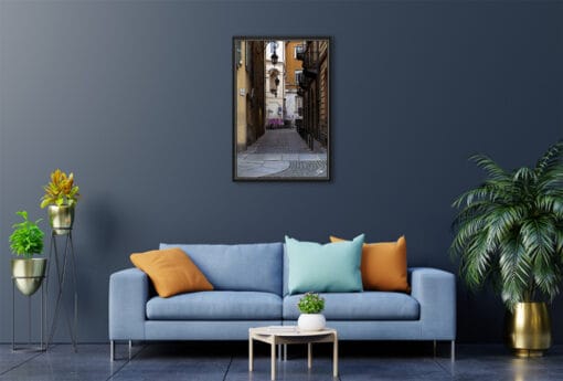 A black framed print of a cobblestone street in Torino, Italy, hanging in a modern living room. By Photographer Scott Allen Wilson.