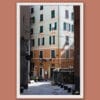 White framed artistic print of a gorgeous alley in Genova, Italy, showcasing the vibrant colors of a building along a downhill cobblestone street. Photo captured by Travel Photographer Scott Allen Wilson.