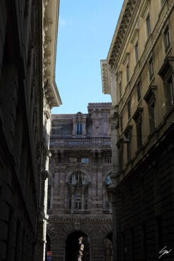 While timeless architectures stand in the core of Genova, a gentle sun creeps through some gaps among the houses, creating scattered highlights on the tall facades.