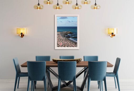 As I observe this brightly lit dining room, I can almost see the elements of the image extending beyond the frame, intertwining with the furniture. The deep blue waves seem to dance among the chairs, while the warm rocky shore unfolds across the wooden table and the golden rays of sunlight hang from the ceiling like glowing lamps.