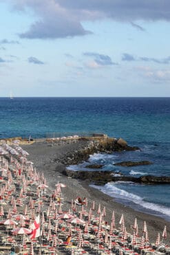 A vast blue sea unfolds beneath a soft sky, its waves gently caressing the warm sandy beach of Genova. Photo captured by Travel Photographer Scott Allen Wilson.