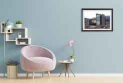 A framed work of art by Travel Photographer Scott Allen Wilson is featured on the wall of a pastel colored room. The color of the sky reflected in the skyscraper seen in the image, almost seems to leak into the blue hue of the room’s color, which perfectly compliments its quaint design.