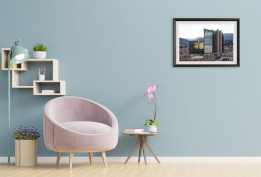 A framed work of art by Travel Photographer Scott Allen Wilson is featured on the wall of a pastel colored room. The color of the sky reflected in the skyscraper seen in the image, almost seems to leak into the blue hue of the room’s color, which perfectly compliments its quaint design.