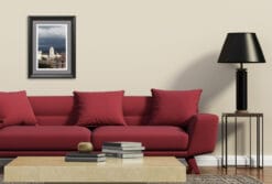 In this sparsely furnished living room, the cream colored walls create a deep contrast with the looming shadows in the image, while the simple black lamp resembles them, bringing the feeling of movement outside of the frame.