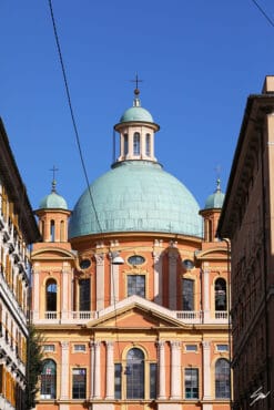 A soft green dome reaches up to a deep blue sky, while the peach and gold walls contrast it vividly. The elegant building stands proudly, blending gracefully with the vibrant sky in the background.