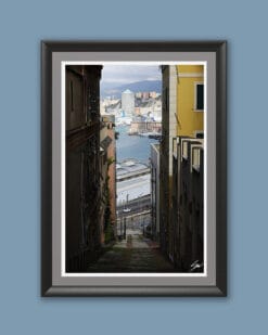 Wooden framed artistic print of a breathtaking portrait shot, showcasing an alley leading down towards the port, while tall buildings frame the image on every side.